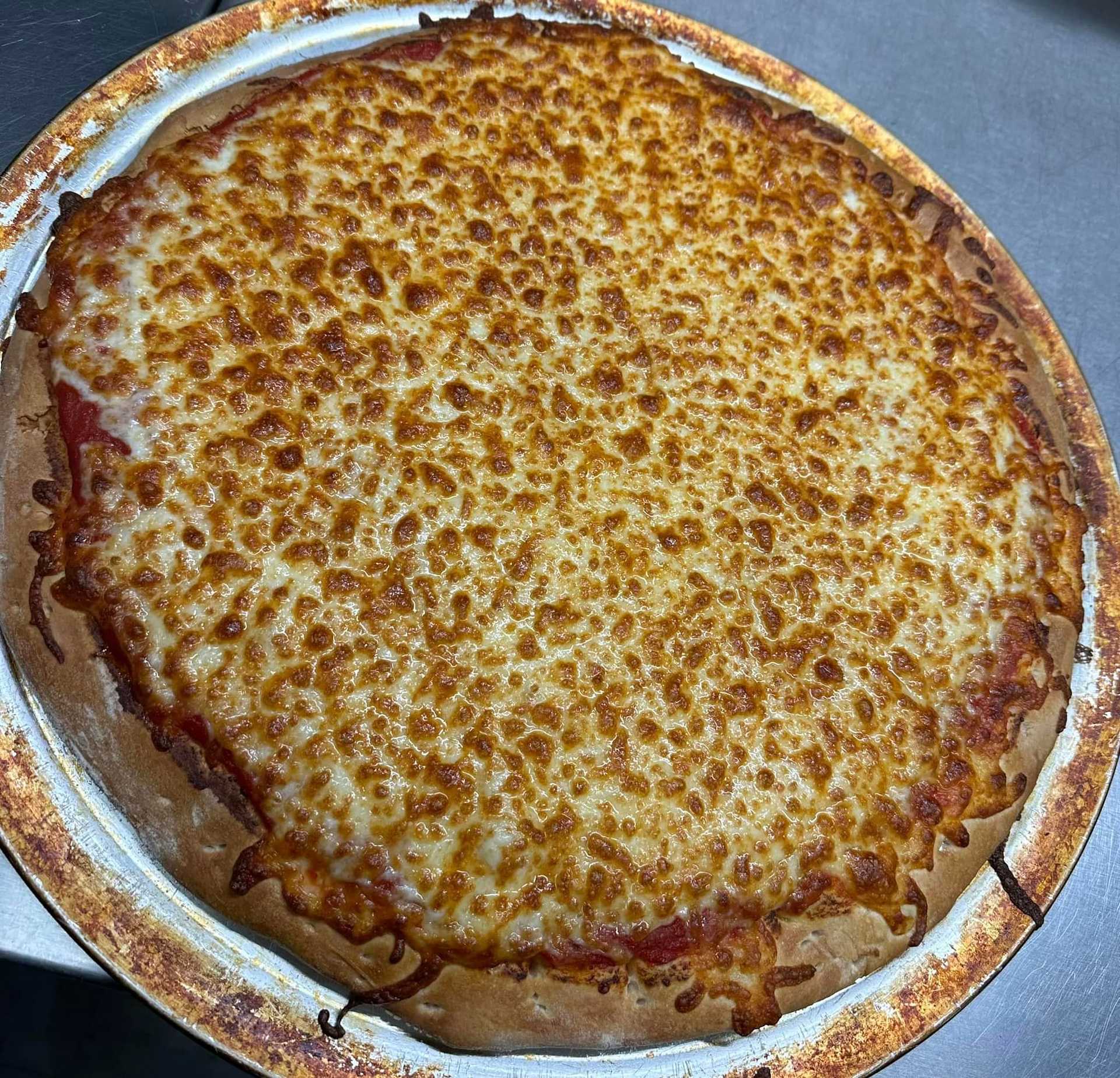 Freshly baked cheese pizza on a metal tray, with a golden brown and bubbly crust.